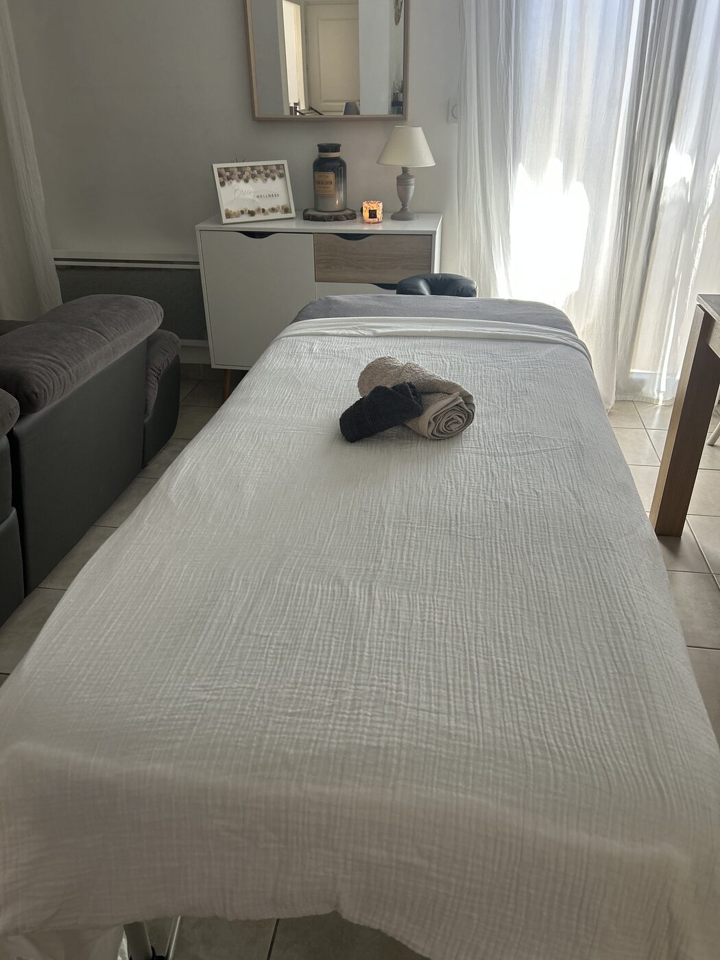 Un cocon de soin installé à domicile : table de massage, linge blanc et lumière douce
